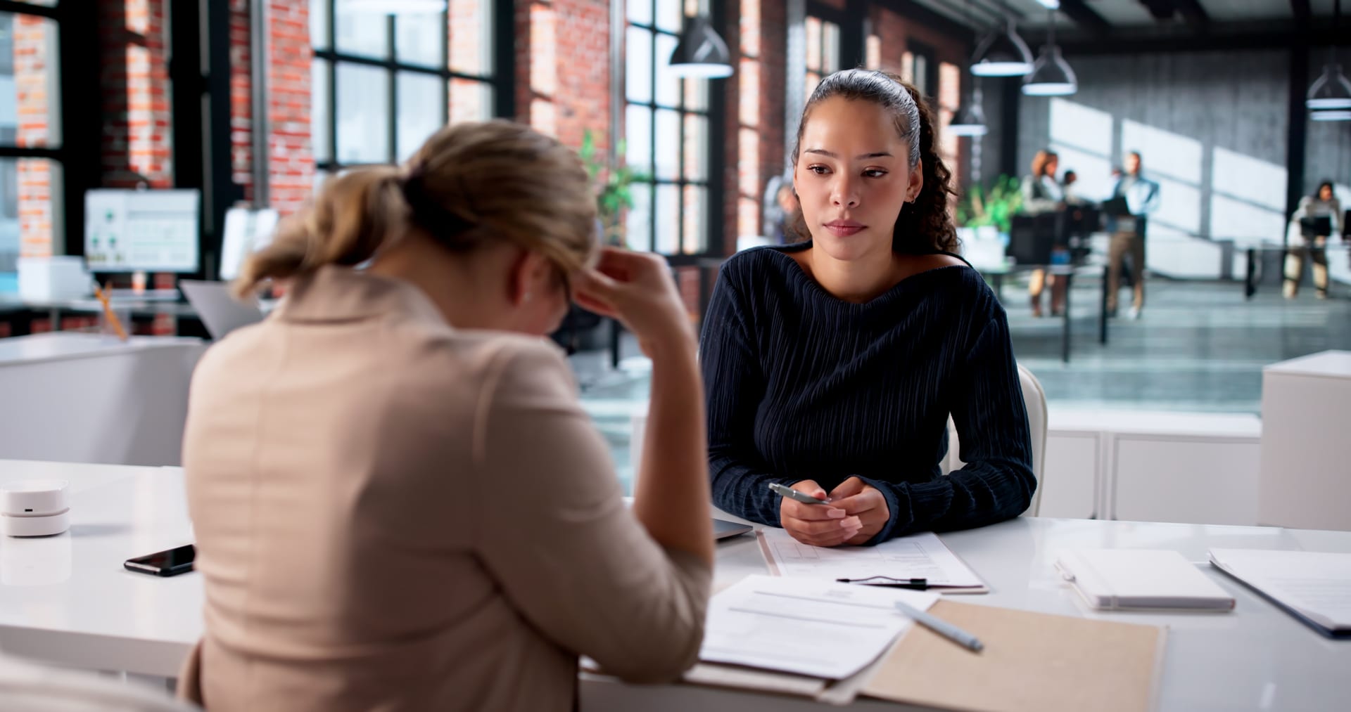 Bewerbungsgespräch in einem modernen Büro: Eine Bewerberin spricht mit einer Personalverantwortlichen über berufliche Herausforderungen und Perspektiven.