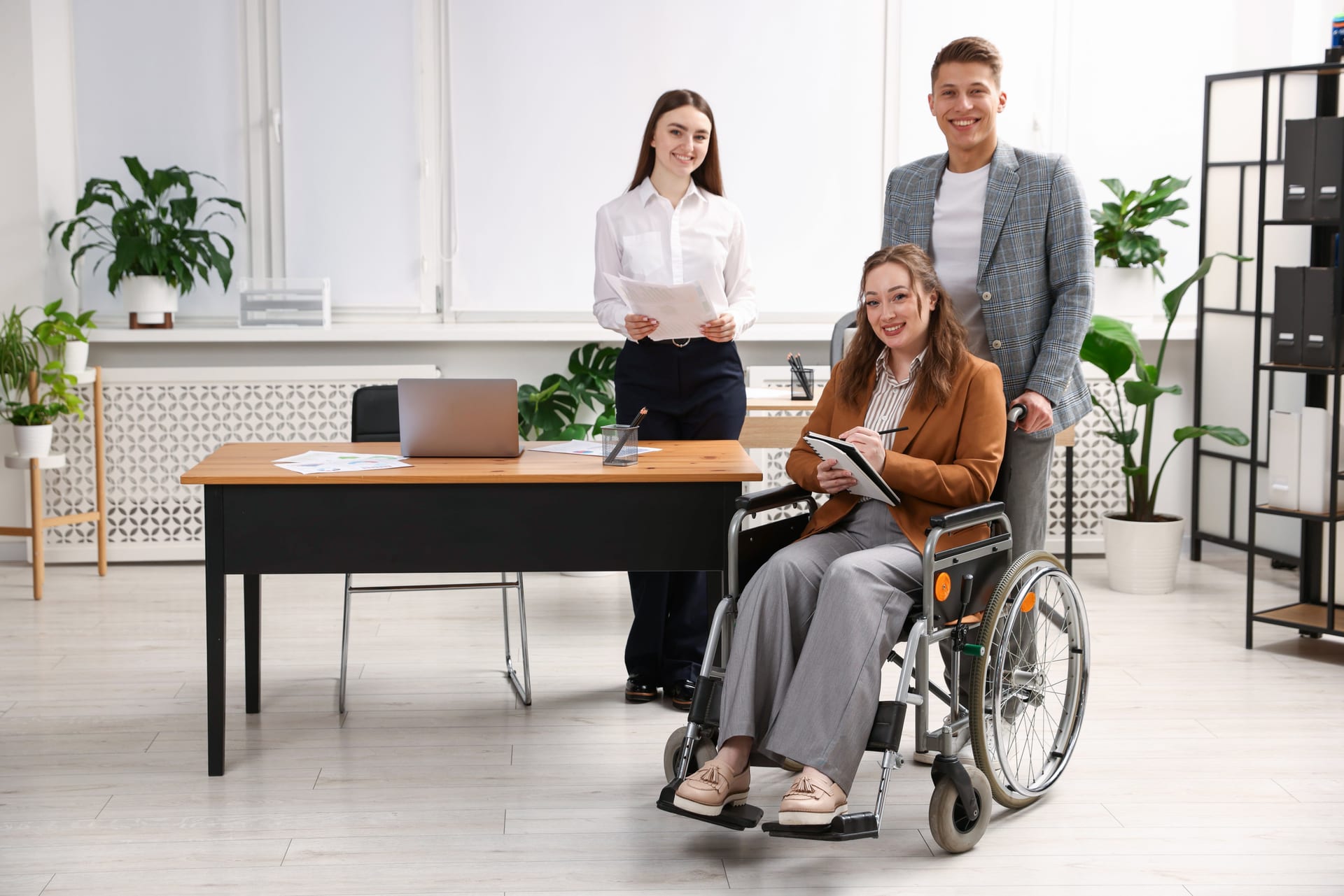 Mitarbeiterin im Rollstuhl arbeitet gemeinsam mit Kolleginnen und Kollegen in einem modernen und inklusiven Büro.